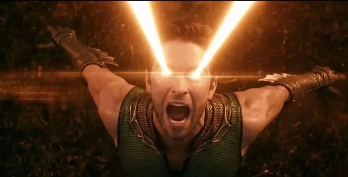The Deep, mid-scream, eyes erupting with golden light, in his green aquatic suit.